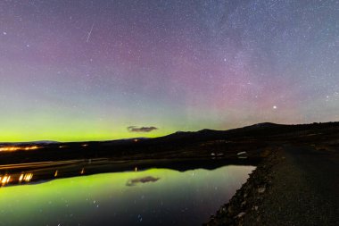 The Northern Lights and Milky Way above the mountains near Dovrefjell National Park, Norway. clipart