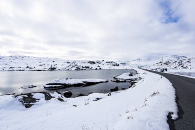 Norveç 'in güneyindeki Sognefjellsvegen yolu boyunca uzanan kış manzarası, karla kaplı dağlar ve geniş, sakin bir arazi içerir..