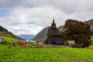 Hopperstad Stavkyrkje in Norway, a historic wooden church surrounded by autumn trees and a peaceful graveyard. clipart