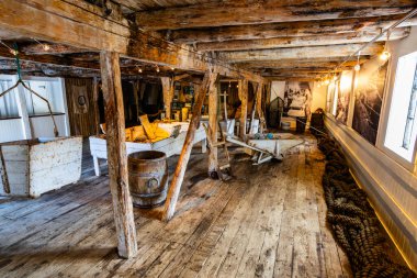 Norveç, Lofoten Adaları 'ndaki Nusfjord manzaralı, kırmızı ve sarı ahşap evler, tekneler ve kristal berrak sularla.