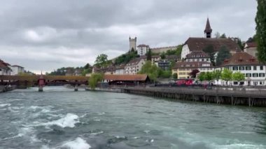 Lucerna, İsviçre; 6 Mayıs 2024: Lucerne, İsviçre 'de bahar günü, gölde tarihi binalar ve bulutlu gökyüzü bulunan bir tekne.