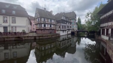 Fransa 'nın Strasbourg şehrinde bahar mevsimi, parlak gökyüzü ve güzel bir nehir boyunca yarım ahşap binalar sergiliyor..