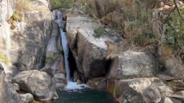 La Cerdanya, Pyrenees, İspanya 'da yaz mevsimi. Etrafı kayalar ve yemyeşil yeşilliklerle çevrili sakin bir şelale sergileniyor..