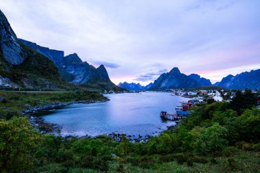 Autumn sunset in Reine, Lofoten Islands, northern Norway, with dramatic mountains, calm waters, and traditional houses along the shore. clipart