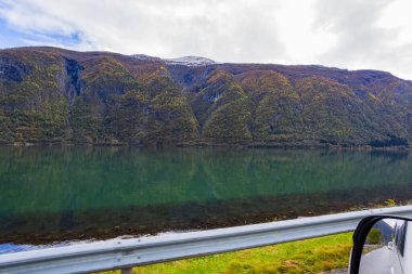 Autumn landscape in Lustrafjorden, Norway, featuring clear water reflections, mountains, and colorful foliage. clipart