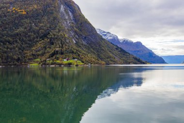 Autumn landscape in Lustrafjorden, Norway, featuring clear water reflections, mountains, and colorful foliage. clipart