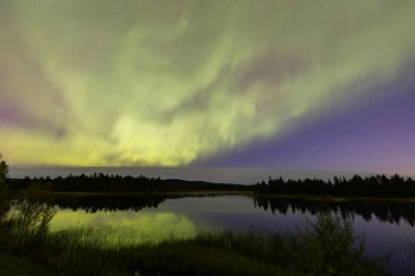 İsveç 'in Kiruna kentindeki kuzey ışıkları Eylül ayında sakin suları yıldızlar ve ormanlarla yansıtıyor..