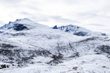 Norveç 'in güneyindeki Sognefjellsvegen yolu boyunca uzanan kış manzarası, karla kaplı dağlar ve geniş, sakin bir arazi içerir..