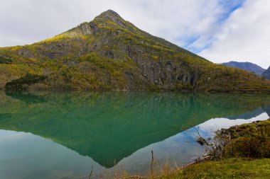 Norveç, Skjolden 'de sonbahar manzarası. Dağları ve renkli yaprakları yansıtan sakin bir göl..