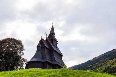 Norveç 'teki Hopperstad Stavkyrkje, güz ağaçları ve huzurlu bir mezarlıkla çevrili tarihi bir ahşap kilise..
