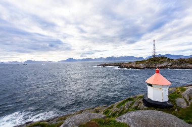 A scenic view of Henningsvaer in Lofoten Islands, Norway, showcasing traditional buildings along the harbor with mountains in the background. clipart