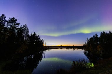 İsveç 'in Kiruna kentindeki kuzey ışıkları Eylül ayında sakin suları yıldızlar ve ormanlarla yansıtıyor..