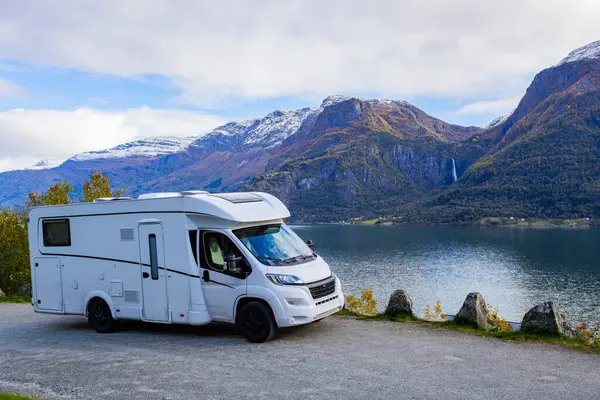 Norveç 'teki sakin Lustrafjorden' in yanında park etmiş bir karavan. Arka planda çarpıcı dağlar ve şelale var..
