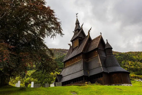 Norveç 'teki Hopperstad Stavkyrkje, güz ağaçları ve huzurlu bir mezarlıkla çevrili tarihi bir ahşap kilise..