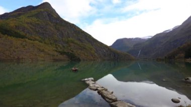 Güney Norveç, Skjolden 'de sonbahar manzarası. Dağları ve renkli yaprakları yansıtan sakin bir göl..