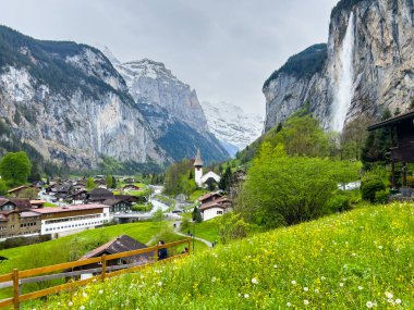 Lauterbrunnen, İsviçre; 5 Mayıs 2024: Lauterbrunnen, İsviçre 'de büyüleyici şelaleler, dağ manzaraları ve büyüleyici köy manzaralarıyla güzel bir bahar günü. 4K UHD