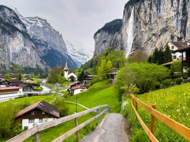 Lauterbrunnen, İsviçre; 5 Mayıs 2024: Lauterbrunnen, İsviçre 'de büyüleyici şelaleler, dağ manzaraları ve büyüleyici köy manzaralarıyla güzel bir bahar günü. 4K UHD