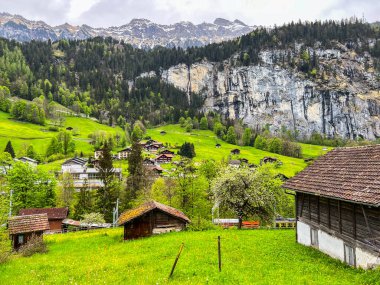 Lauterbrunnen, İsviçre; 5 Mayıs 2024: Lauterbrunnen, İsviçre 'de büyüleyici şelaleler, dağ manzaraları ve büyüleyici köy manzaralarıyla güzel bir bahar günü. 4K UHD