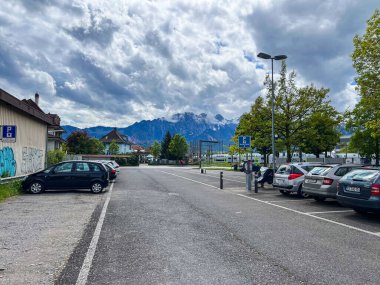 Thun, İsviçre; 5 Mayıs 2024: İsviçre alp dağları ve arka planda bulutlu gökyüzü ile boş otopark