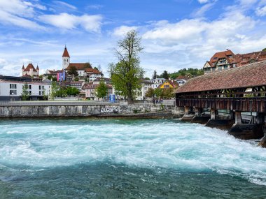 Thun, İsviçre; 5 Mayıs 2024: Thun, İsviçre 'de tarihi binalar, akan bir nehir ve güzel bir gökyüzü ile büyüleyici bir bahar sahnesi. 4K UHD