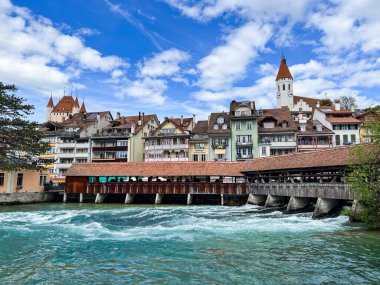 Thun, İsviçre; 5 Mayıs 2024: Thun, İsviçre 'de tarihi binalar, akan bir nehir ve güzel bir gökyüzü ile büyüleyici bir bahar sahnesi. 4K UHD
