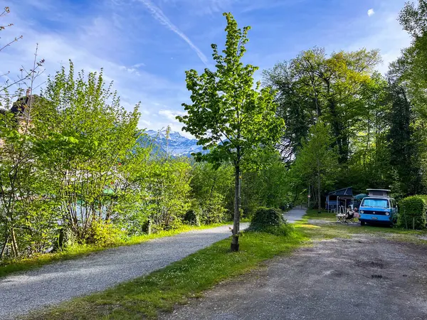 Interlaken, İsviçre; 4 Mayıs 2024: İsviçre 'nin Interlaken kentinde sakin bir bahar günü, pikoresk dağları yakınlarındaki bir kamp alanında kampçılar yer alıyor.