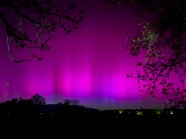 La Cerdanya, Pyrenees, İspanya 'da gece gökyüzünde dans eden canlı mor ve mor kuzey ışıkları. Mayıs 2024
