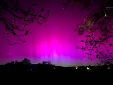 La Cerdanya, Pyrenees, İspanya 'da gece gökyüzünde dans eden canlı mor ve mor kuzey ışıkları. Mayıs 2024