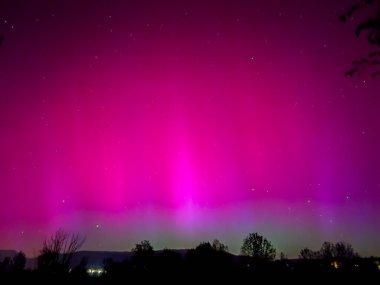 La Cerdanya, Pyrenees, İspanya 'da gece gökyüzünde dans eden canlı mor ve mor kuzey ışıkları. Mayıs 2024