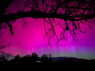 La Cerdanya, Pyrenees, İspanya 'da gece gökyüzünde dans eden canlı mor ve mor kuzey ışıkları. Mayıs 2024