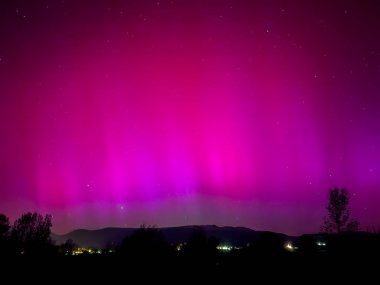 La Cerdanya, Pyrenees, İspanya 'da gece gökyüzünde dans eden canlı mor ve mor kuzey ışıkları. Mayıs 2024