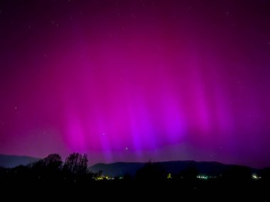 La Cerdanya, Pyrenees, İspanya 'da gece gökyüzünde dans eden canlı mor ve mor kuzey ışıkları. Mayıs 2024