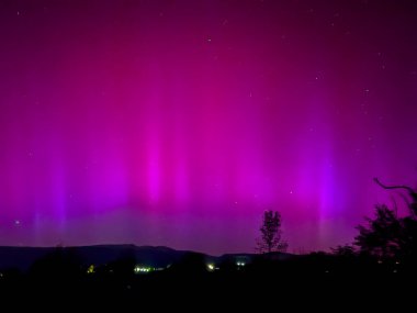 La Cerdanya, Pyrenees, İspanya 'da gece gökyüzünde dans eden canlı mor ve mor kuzey ışıkları. Mayıs 2024