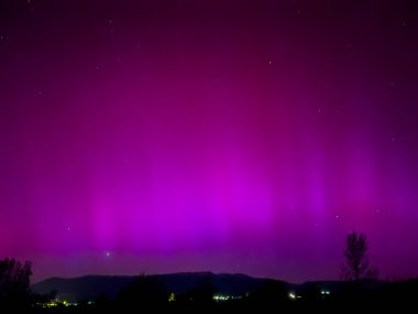 La Cerdanya, Pyrenees, İspanya 'da gece gökyüzünde dans eden canlı mor ve mor kuzey ışıkları. Mayıs 2024