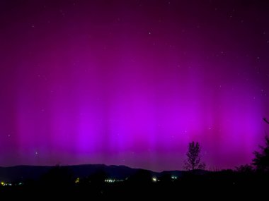 La Cerdanya, Pyrenees, İspanya 'da gece gökyüzünde dans eden canlı mor ve mor kuzey ışıkları. Mayıs 2024
