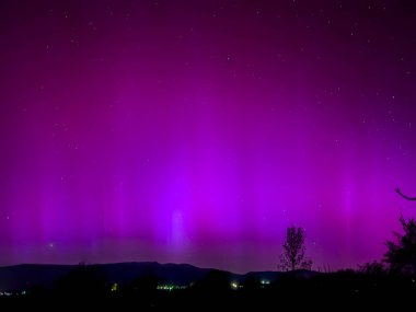 La Cerdanya, Pyrenees, İspanya 'da gece gökyüzünde dans eden canlı mor ve mor kuzey ışıkları. Mayıs 2024