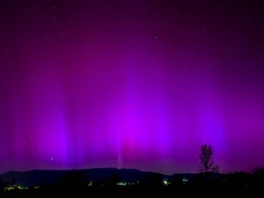 La Cerdanya, Pyrenees, İspanya 'da gece gökyüzünde dans eden canlı mor ve mor kuzey ışıkları. Mayıs 2024