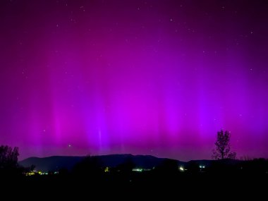La Cerdanya, Pyrenees, İspanya 'da gece gökyüzünde dans eden canlı mor ve mor kuzey ışıkları. Mayıs 2024