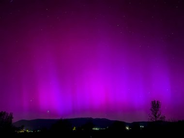 La Cerdanya, Pyrenees, İspanya 'da gece gökyüzünde dans eden canlı mor ve mor kuzey ışıkları. Mayıs 2024