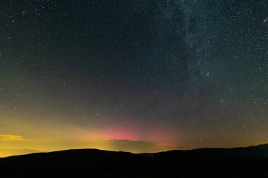 Aurora borealis gece gökyüzünü parlak renklerle aydınlatıyor, Coll De La Creueta, Pyrenees, Barselona, İspanya 'daki sayısız yıldızın ardından kayan yıldızlar. Ağustos 2024