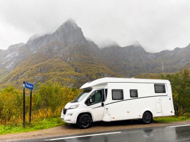 Yağmurlu bir sonbahar gününde Norveç, Bodalen 'de manzaralı bir dağ manzaralı yol kenarına park edilmiş beyaz bir karavan.