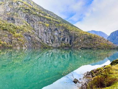 Autumn landscape in Skjolden, Norway, with a calm lake reflecting the mountains and colorful foliage. clipart