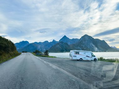 Motorhomes at sunrise with the stunning reflection of mountains and scenic landscape in Reine, Lofoten Islands, northern Norway. clipart