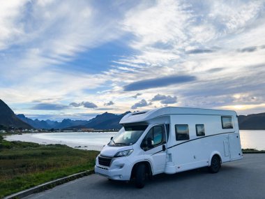 Kuzey Norveç 'teki Reine, Lofoten Adaları' ndaki dağların ve manzaranın çarpıcı yansımasıyla gün doğumunda motorlu evler.