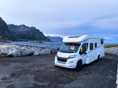 Kuzey Norveç 'teki Reine, Lofoten Adaları' ndaki dağların ve manzaranın çarpıcı yansımasıyla gün doğumunda motorlu evler.