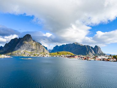 Norveç 'in Hamnoy, Lofoten Adaları' nda gün doğumu, kıyı şeridi boyunca geleneksel kırmızı evler ve dramatik dağlar..