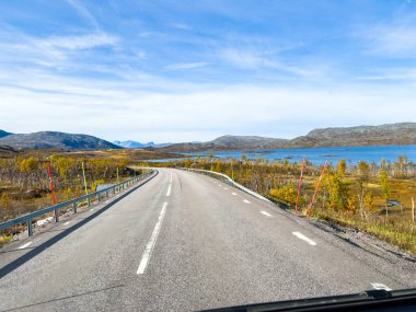 İsveç 'in Kiruna şehrinde sonbahar yeşillikleri ve güzel göl manzaralı bir yolda karavanla yolculuk yapmak..