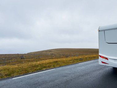 Yağmurlu ve sisli bir günde Nordkapp, Norveç 'e giden e69 yolunda giden beyaz bir karavan.