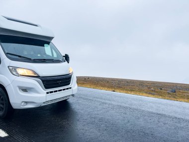 Yağmurlu ve sisli bir günde Nordkapp, Norveç 'e giden e69 yolunda giden beyaz bir karavan.