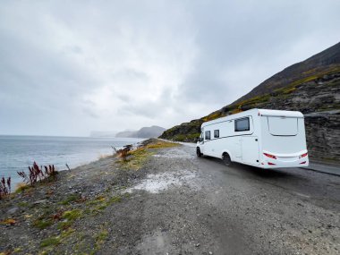 Yağmurlu ve sisli bir günde Nordkapp, Norveç 'e giden e69 yolunda giden beyaz bir karavan.